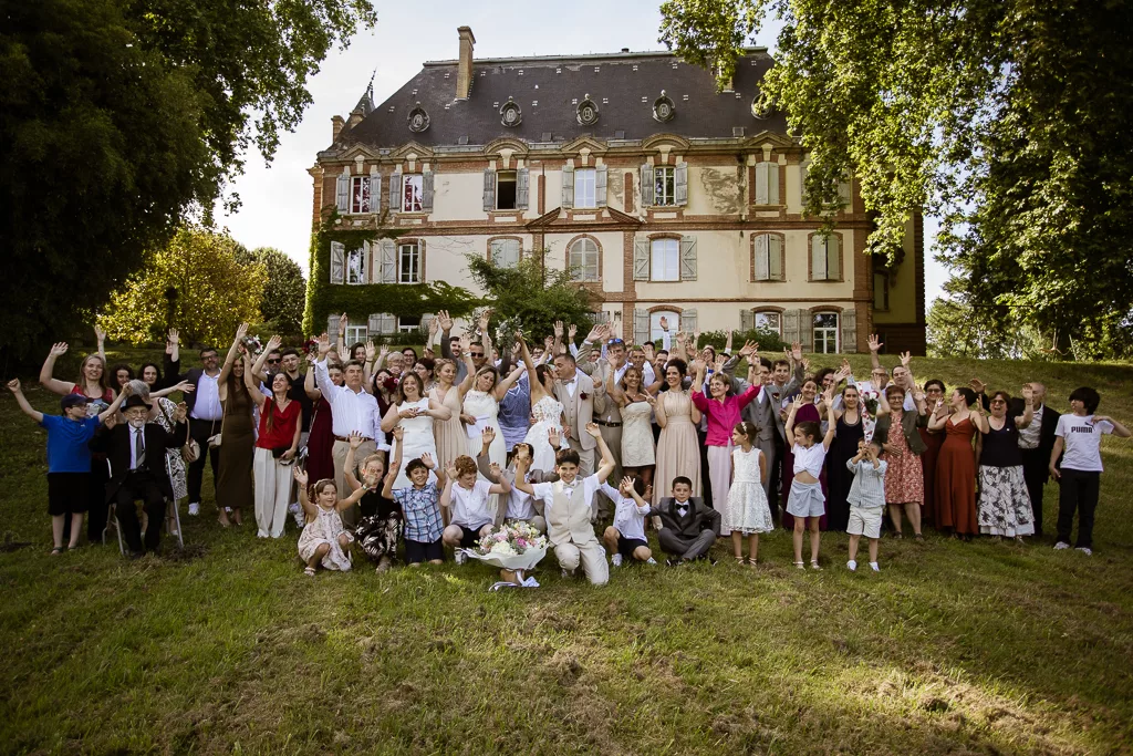 Photo générale des mariés et de leurs invités devant la façade du chateau Saint Marcel